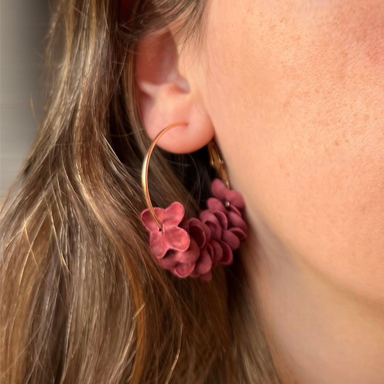 Aros dorados con pétalos de flores burdeos
