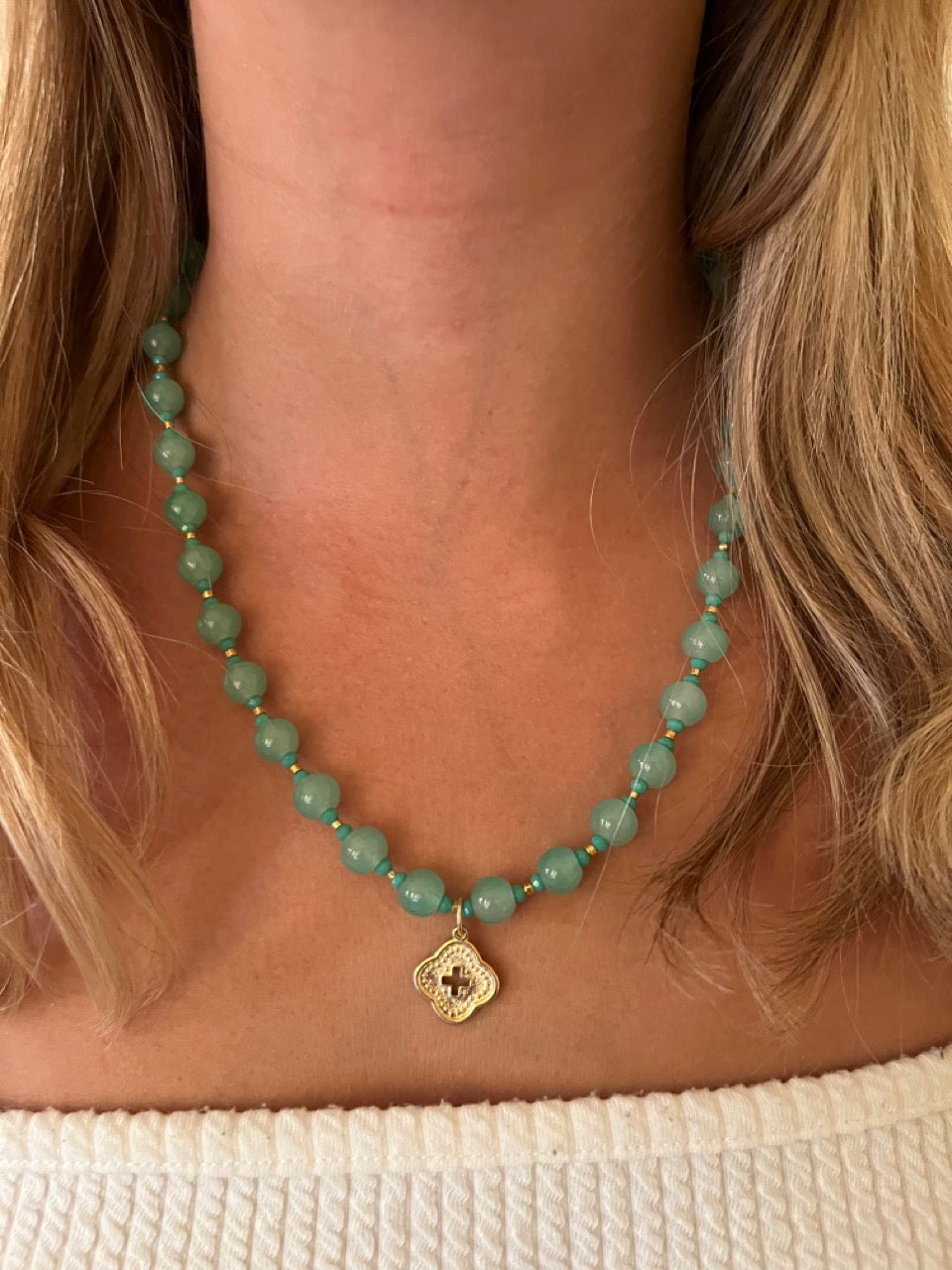 Collar con ágatas verdes y cruz dorada en forma de rombo.